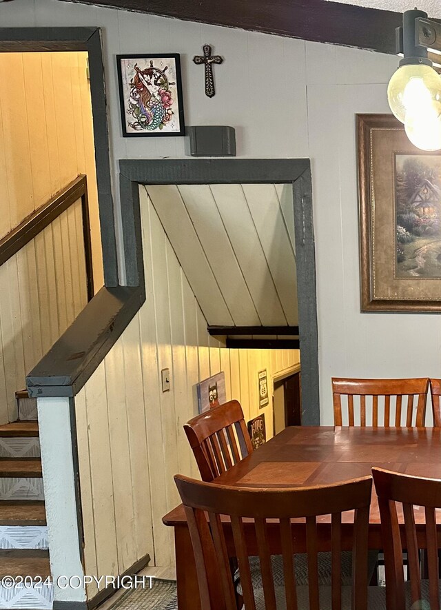 dining room with wood walls and vaulted ceiling