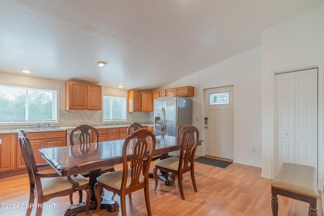 dining area with lofted ceiling, sink, and light hardwood / wood-style flooring