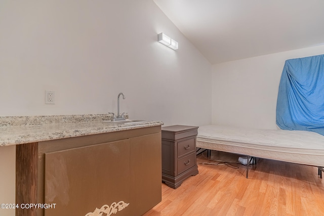 bathroom with sink, hardwood / wood-style flooring, and vaulted ceiling