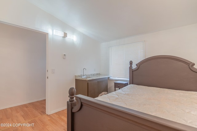 bedroom with lofted ceiling, sink, and light wood-type flooring