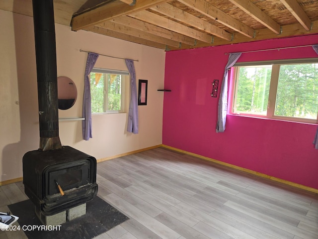 interior space featuring beamed ceiling, hardwood / wood-style flooring, and a wood stove