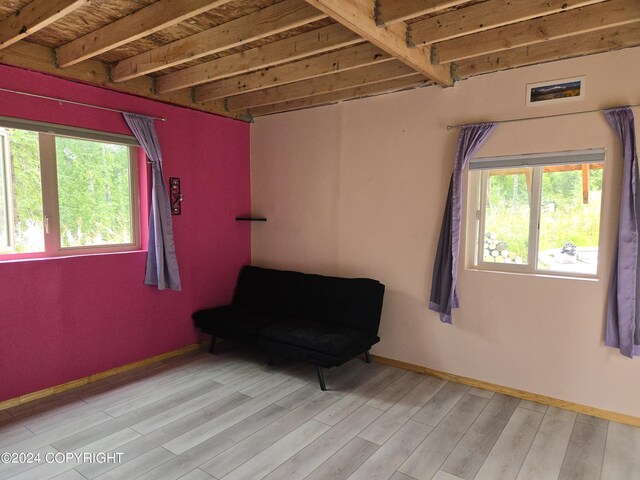 unfurnished room with light hardwood / wood-style floors and beamed ceiling