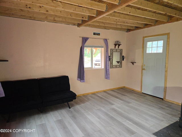 unfurnished room with plenty of natural light, light wood-type flooring, and beam ceiling