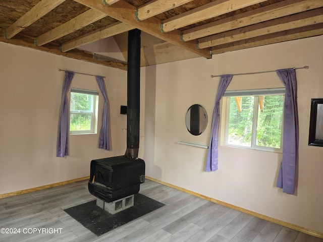 interior space with beam ceiling, light wood-type flooring, and a wood stove