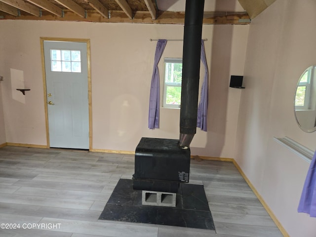 interior space with light hardwood / wood-style floors, beam ceiling, and a wood stove