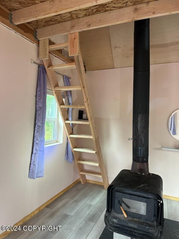 staircase with wood-type flooring and a wood stove