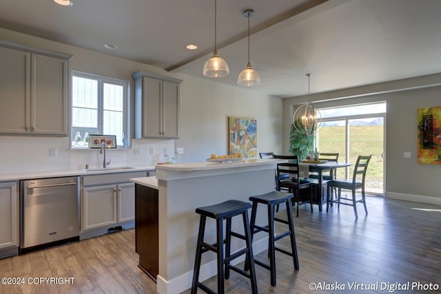 kitchen with decorative light fixtures, gray cabinets, light countertops, stainless steel dishwasher, and a sink