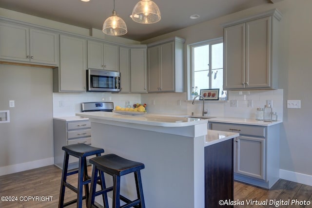 kitchen with appliances with stainless steel finishes, a center island, light countertops, pendant lighting, and a sink