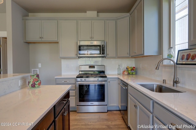 kitchen featuring sink, tasteful backsplash, light hardwood / wood-style floors, and stainless steel appliances