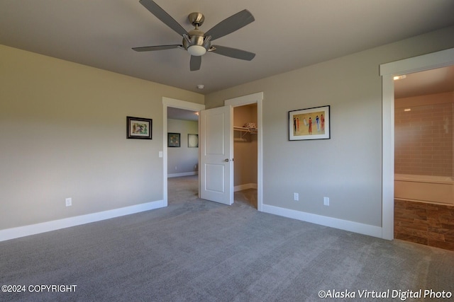 unfurnished bedroom featuring carpet floors, ensuite bathroom, ceiling fan, and a walk in closet