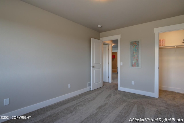 unfurnished bedroom featuring a walk in closet, carpet flooring, and a closet