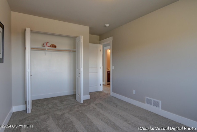 unfurnished bedroom with light colored carpet and a closet