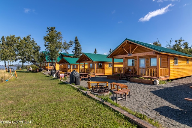 rear view of property with a fire pit, a lawn, log veneer siding, metal roof, and a wooden deck