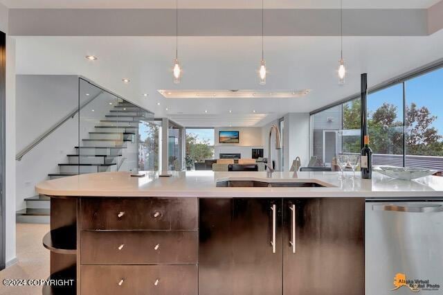 kitchen with a sink, light countertops, stainless steel dishwasher, and open floor plan