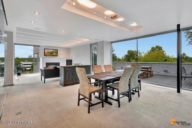 dining area with a wall of windows and a warm lit fireplace