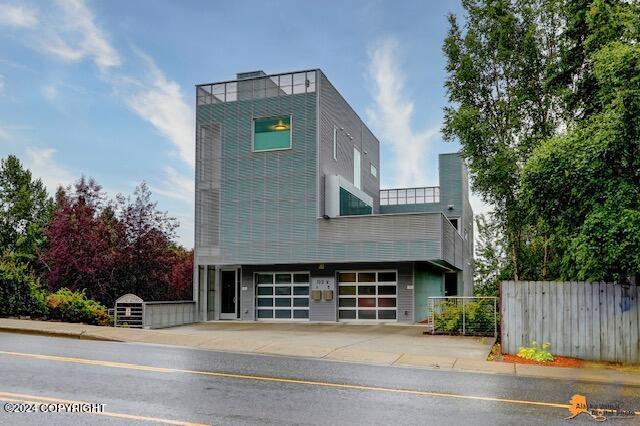 contemporary home with concrete driveway, an attached garage, and fence