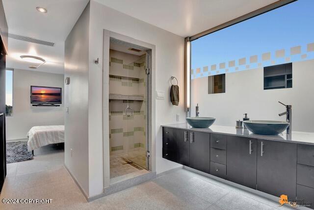 ensuite bathroom featuring double vanity, a stall shower, a sink, and ensuite bathroom