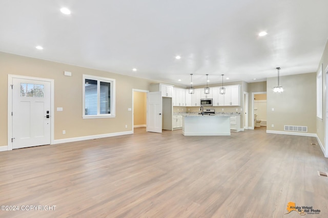 unfurnished living room with an inviting chandelier and light hardwood / wood-style floors