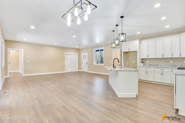 kitchen featuring pendant lighting, white cabinetry, sink, light hardwood / wood-style floors, and light stone countertops