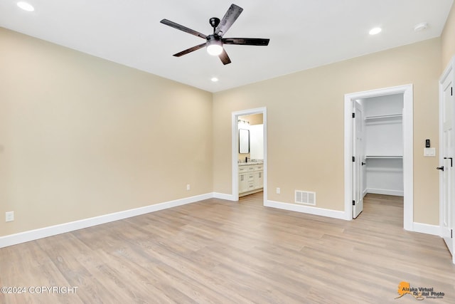 unfurnished bedroom with a walk in closet, ensuite bathroom, a closet, and light hardwood / wood-style flooring