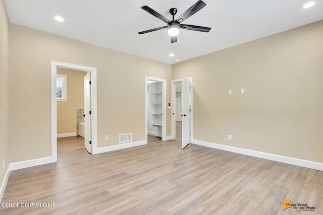 unfurnished bedroom with a walk in closet, connected bathroom, light hardwood / wood-style floors, and a closet