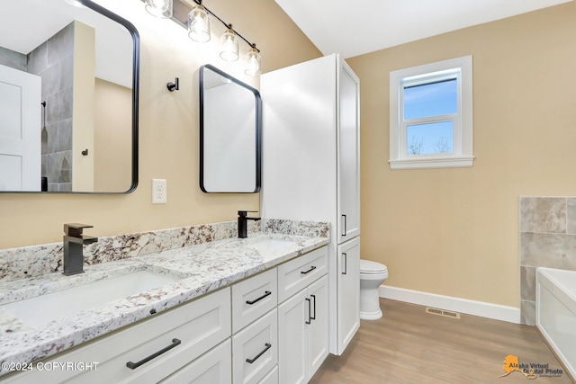 bathroom with vanity, toilet, a bathing tub, and hardwood / wood-style floors