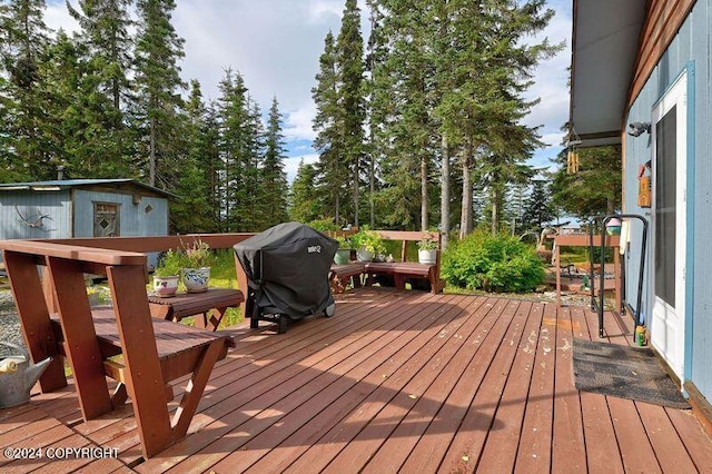 wooden deck with a shed and a grill