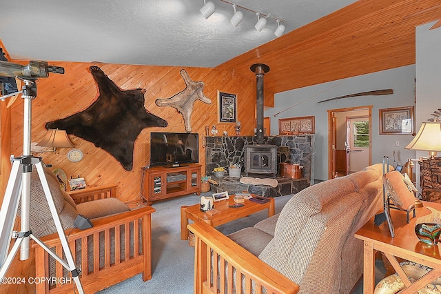 living room featuring a textured ceiling, a wood stove, vaulted ceiling, and wooden walls