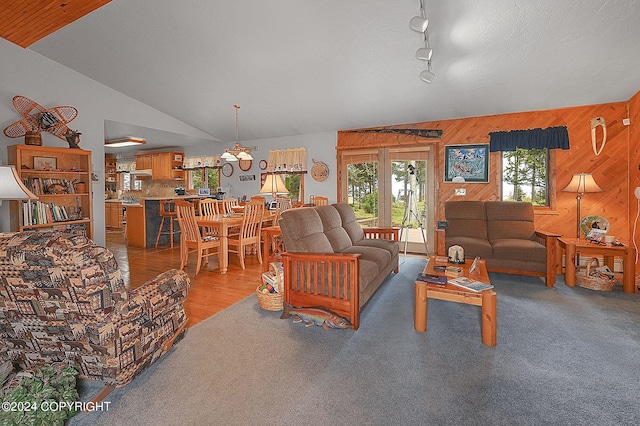 living room featuring wood walls, track lighting, lofted ceiling, and hardwood / wood-style floors