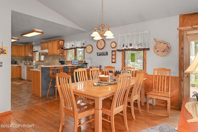 dining space featuring lofted ceiling, a notable chandelier, light wood-type flooring, and a healthy amount of sunlight