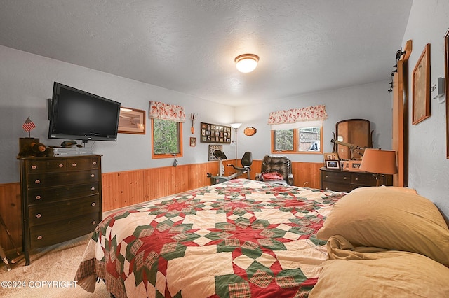 bedroom featuring a textured ceiling, wooden walls, and light colored carpet