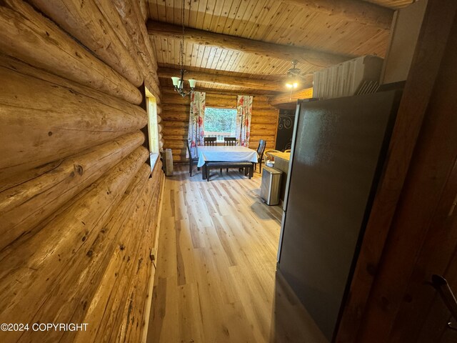 unfurnished bedroom featuring an inviting chandelier, beamed ceiling, light hardwood / wood-style flooring, wood ceiling, and rustic walls