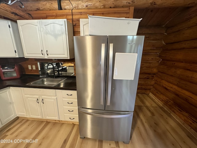 kitchen with light wood-type flooring, log walls, wooden ceiling, sink, and stainless steel fridge