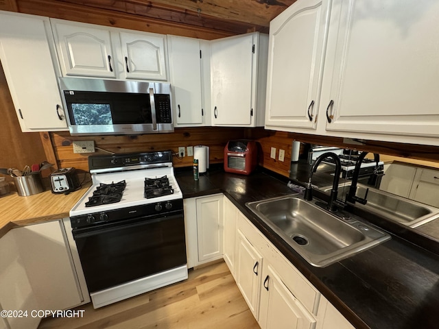 kitchen featuring light wood-type flooring, white cabinets, sink, and white gas range