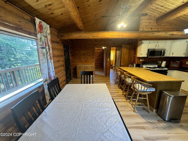 dining space with ceiling fan, lofted ceiling with beams, and light hardwood / wood-style flooring