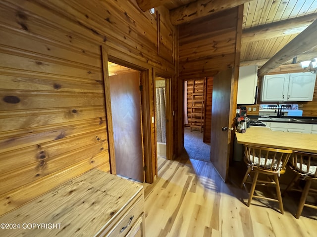 interior space featuring wooden walls, wooden ceiling, beamed ceiling, and light wood-type flooring