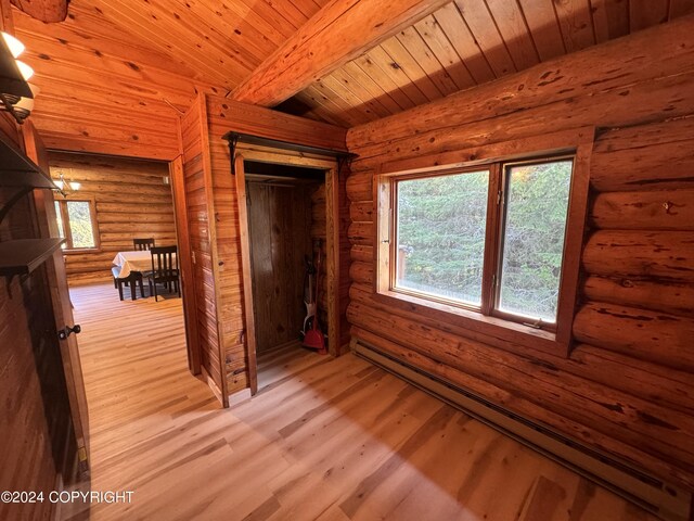 unfurnished bedroom featuring log walls, light wood-type flooring, vaulted ceiling with beams, wood ceiling, and baseboard heating