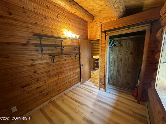 interior space with light hardwood / wood-style flooring, wooden walls, wooden ceiling, and a closet