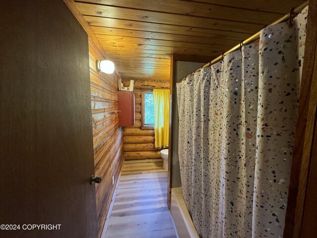 bathroom featuring wood-type flooring, toilet, rustic walls, and wood ceiling