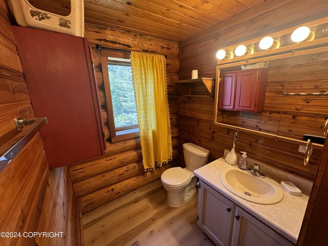 bathroom featuring hardwood / wood-style flooring, vanity, log walls, and toilet