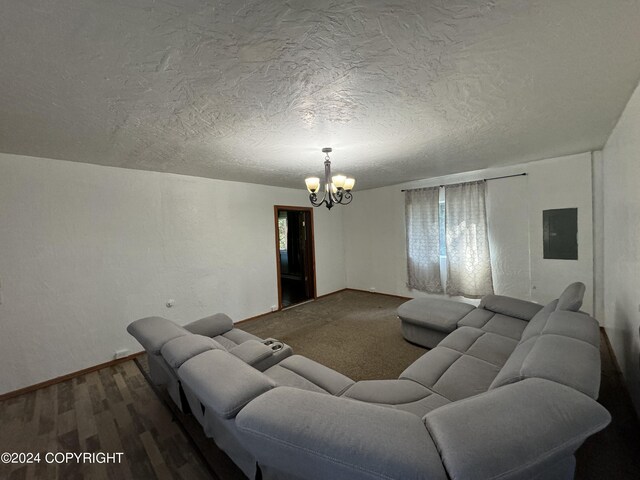 living room featuring hardwood / wood-style flooring, a notable chandelier, a textured ceiling, and electric panel