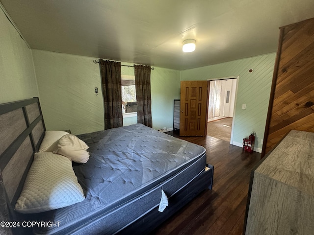 bedroom featuring wooden walls and dark wood-type flooring