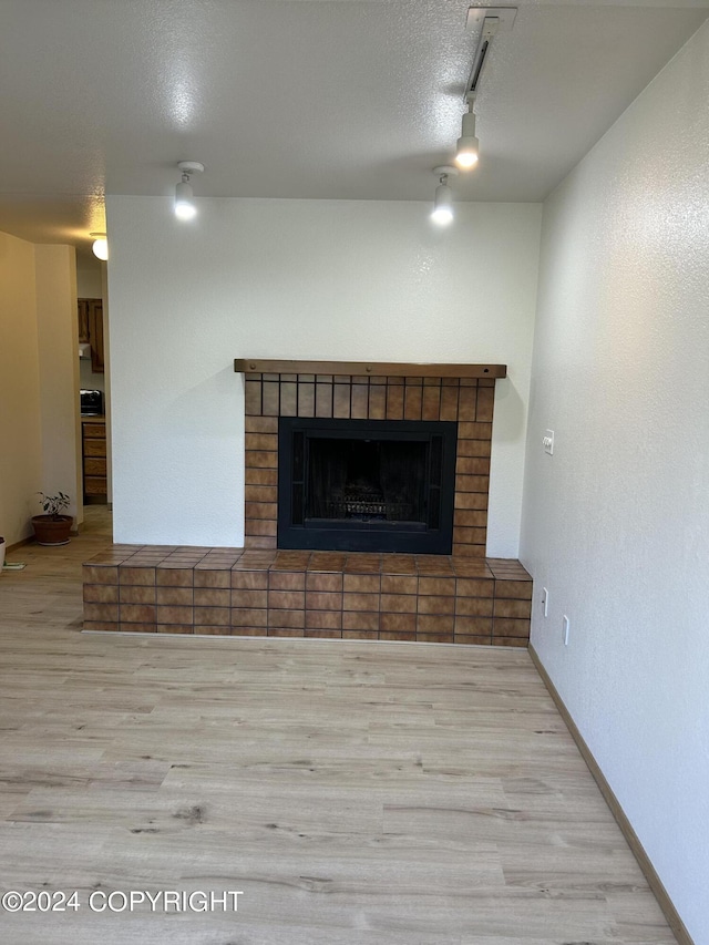 details featuring a textured ceiling, a brick fireplace, track lighting, and hardwood / wood-style flooring