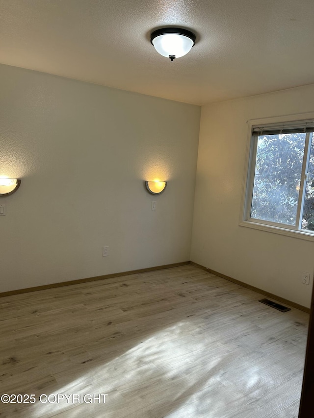 spare room featuring light wood-type flooring and a textured ceiling