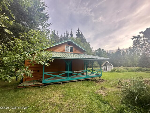 back of property featuring a yard and an outbuilding