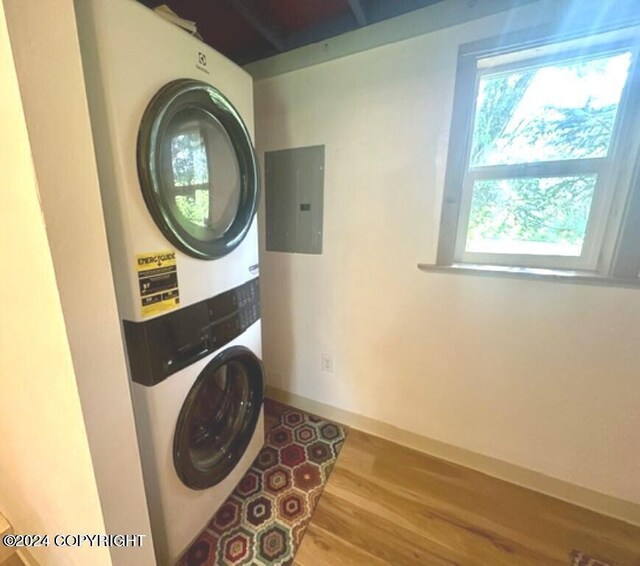 laundry area with stacked washing maching and dryer, electric panel, and hardwood / wood-style floors