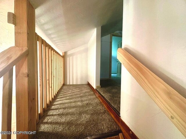 hallway with a textured ceiling and carpet flooring