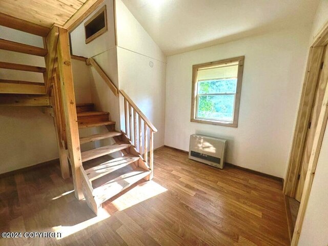 stairs featuring lofted ceiling, hardwood / wood-style floors, wood ceiling, and heating unit