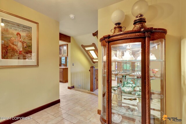 corridor featuring light tile patterned flooring and a skylight