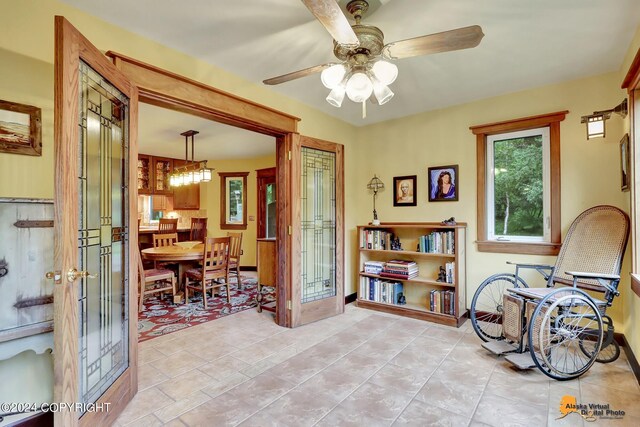 interior space with french doors and ceiling fan with notable chandelier